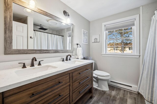 full bathroom with a sink, toilet, wood finished floors, and a baseboard radiator