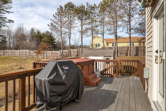 deck with a hot tub, a grill, an outdoor structure, and a fenced backyard