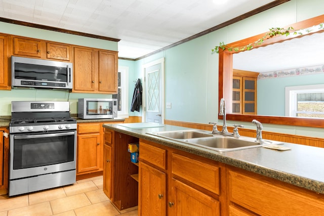 kitchen with a sink, stainless steel appliances, brown cabinets, and crown molding