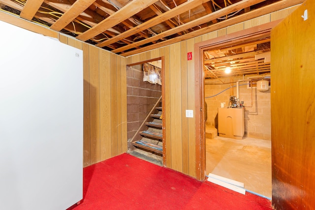 unfinished basement featuring stairway and concrete block wall