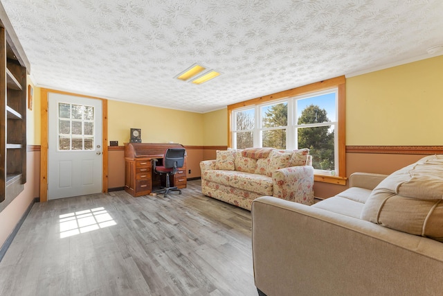 living area with ornamental molding, a textured ceiling, and wood finished floors