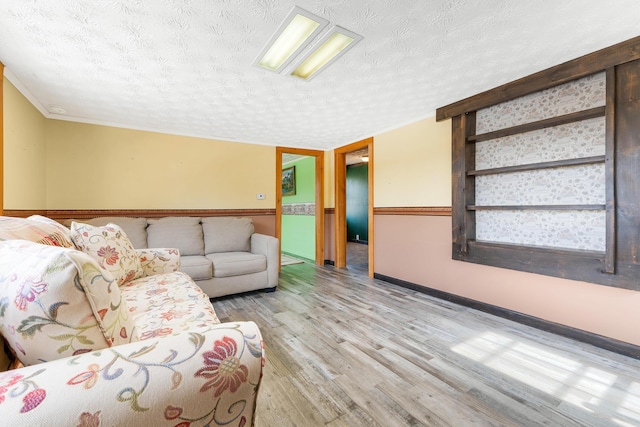 unfurnished living room with crown molding, baseboards, light wood-type flooring, and a textured ceiling