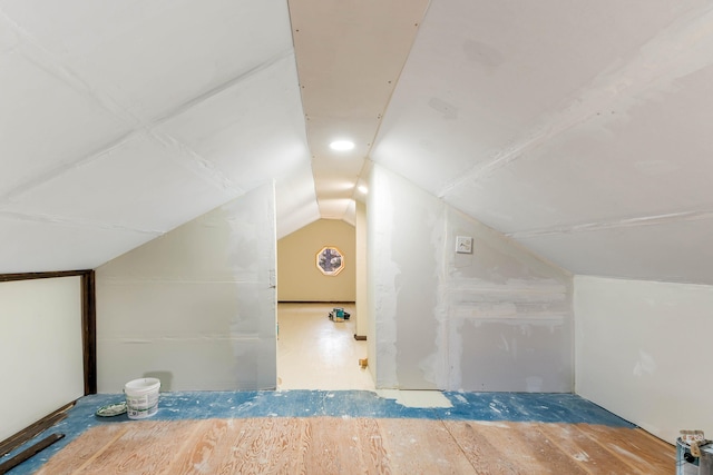 additional living space with wood finished floors and vaulted ceiling