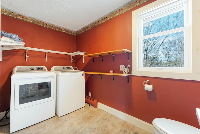 clothes washing area featuring baseboards, separate washer and dryer, laundry area, and a textured ceiling