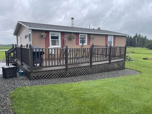 rear view of property with a shingled roof, a lawn, and a wooden deck