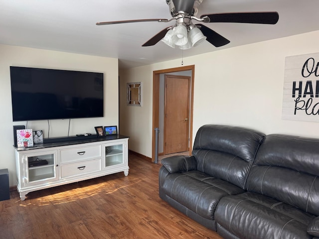 living area featuring ceiling fan, dark wood-type flooring, and baseboards