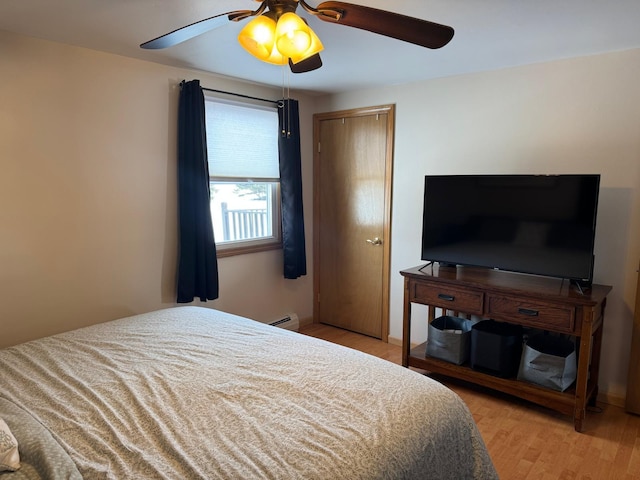 bedroom featuring light wood finished floors, baseboard heating, and ceiling fan