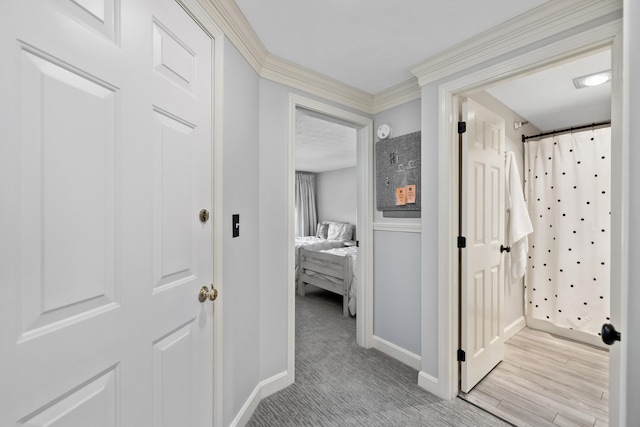 hallway with light carpet, baseboards, and ornamental molding