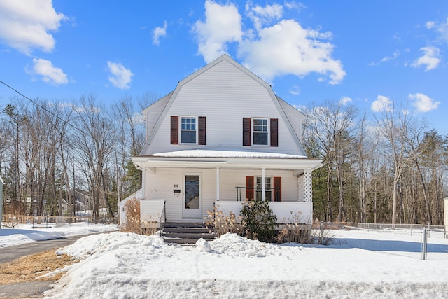 dutch colonial featuring a gambrel roof, a porch, and fence