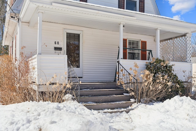 snow covered property entrance featuring a porch