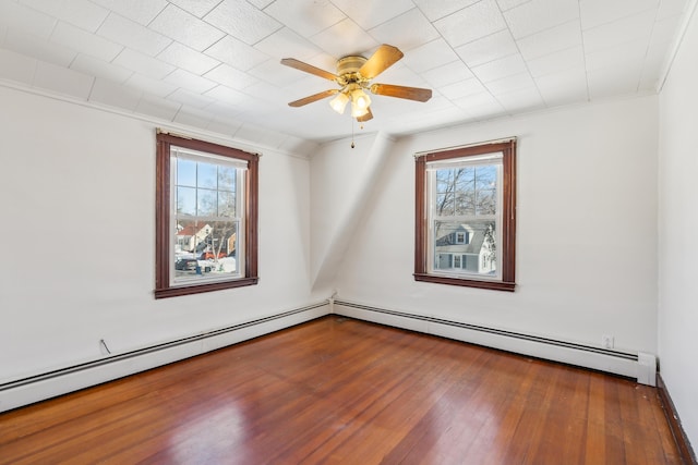 unfurnished room with a wealth of natural light, baseboard heating, and hardwood / wood-style flooring