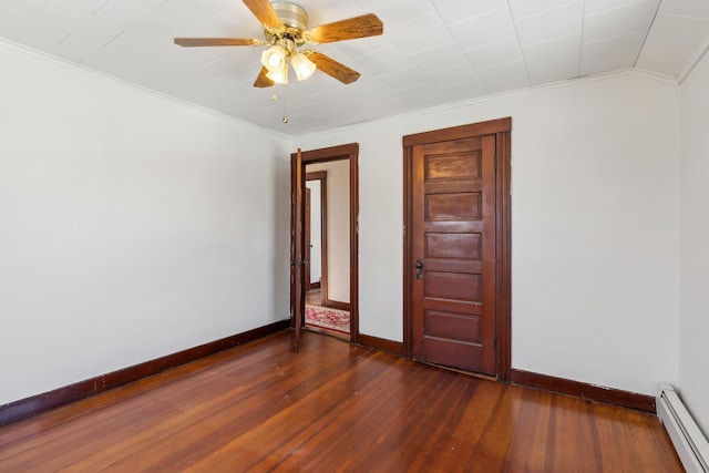 empty room with baseboard heating, dark wood-type flooring, and ornamental molding