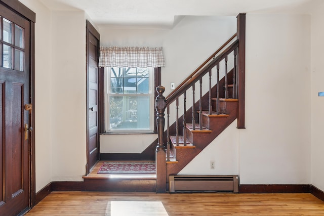 foyer featuring stairway, a baseboard heating unit, baseboards, and wood finished floors