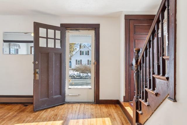 entrance foyer with stairway, light wood-style flooring, baseboards, and a baseboard radiator