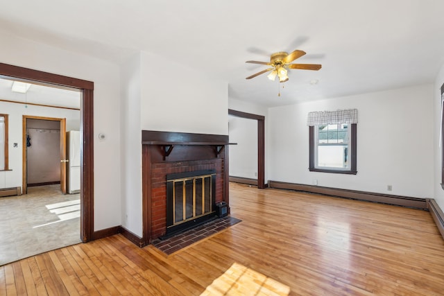 unfurnished living room with a ceiling fan, a brick fireplace, light wood-style flooring, and a baseboard radiator