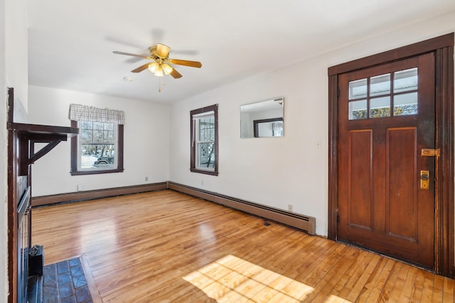 entrance foyer featuring a baseboard radiator, plenty of natural light, and light wood-style flooring