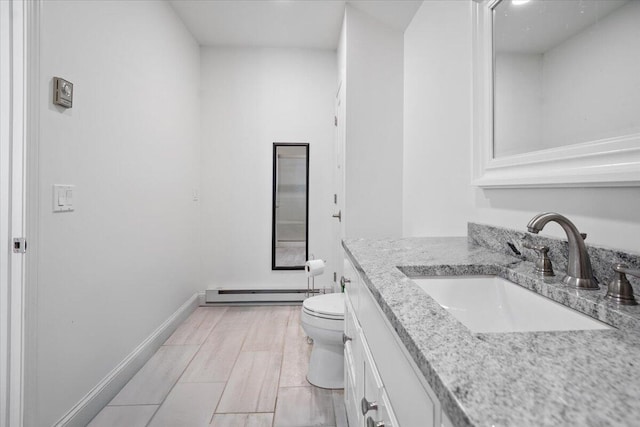 bathroom featuring vanity, baseboards, wood finish floors, a baseboard radiator, and toilet