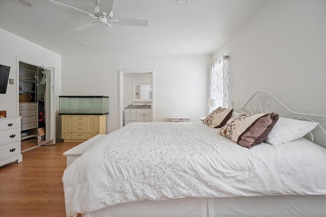 bedroom featuring ceiling fan, a closet, ensuite bath, and wood finished floors