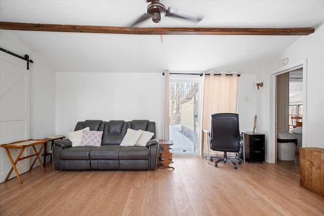 living room featuring a barn door, vaulted ceiling with beams, light wood-style floors, and ceiling fan