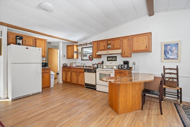 kitchen featuring white appliances, brown cabinetry, lofted ceiling, a peninsula, and under cabinet range hood