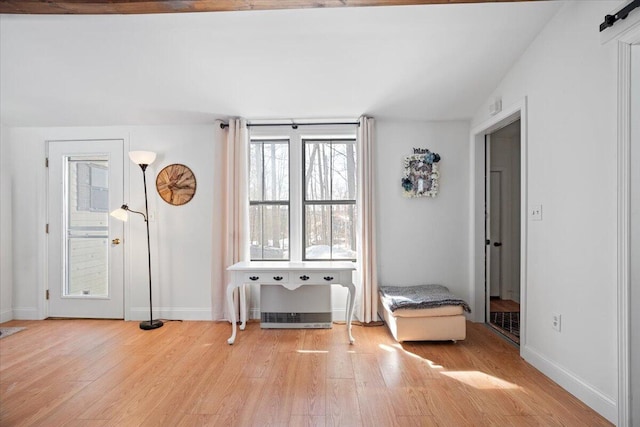 interior space with vaulted ceiling, wood finished floors, baseboards, and visible vents