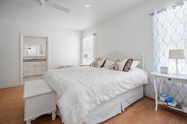 bedroom featuring baseboards, multiple windows, and light wood-style flooring