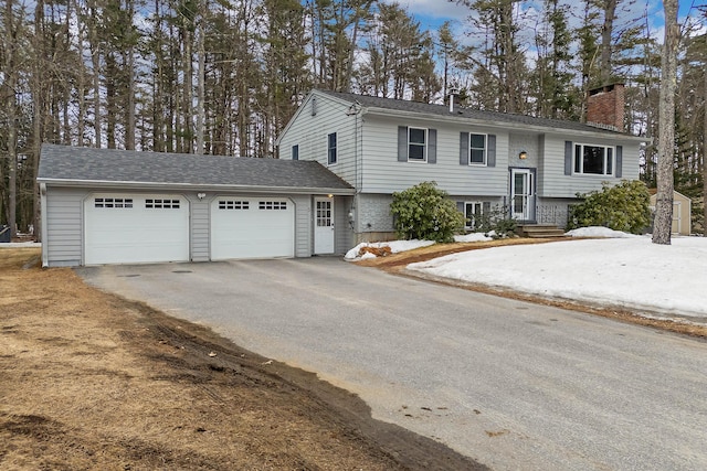 split foyer home with aphalt driveway, a chimney, and a garage