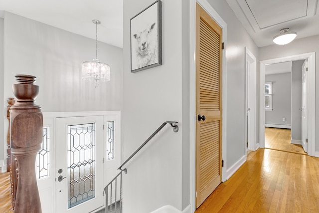 foyer featuring a baseboard heating unit, a notable chandelier, baseboards, and light wood finished floors