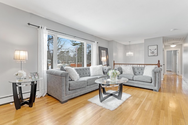 living area with a notable chandelier, attic access, and light wood-style flooring