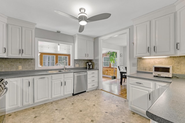 kitchen featuring decorative backsplash, appliances with stainless steel finishes, white cabinets, a ceiling fan, and a sink