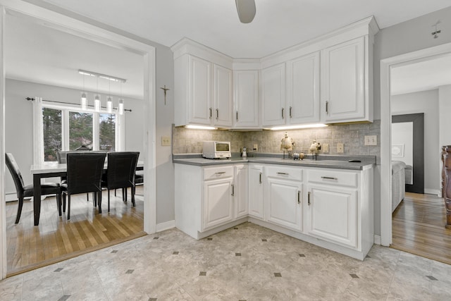 kitchen with tasteful backsplash, a toaster, white cabinets, and light wood-style flooring