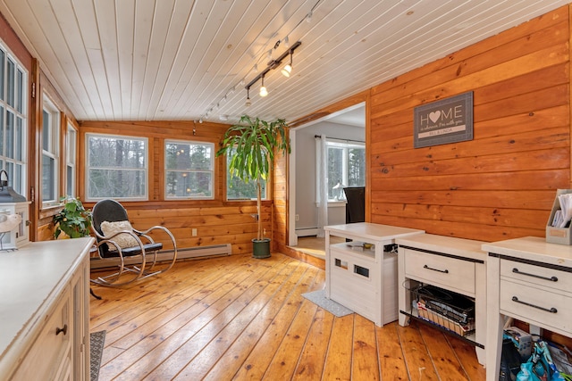 interior space featuring light wood finished floors, a baseboard heating unit, wood walls, wood ceiling, and light countertops