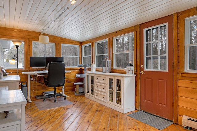 office area with a baseboard heating unit, lofted ceiling, wooden walls, and light wood finished floors