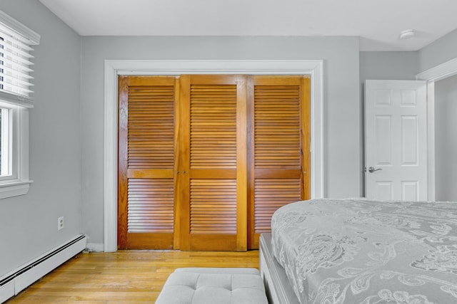 bedroom featuring light wood-style floors, a closet, and baseboard heating