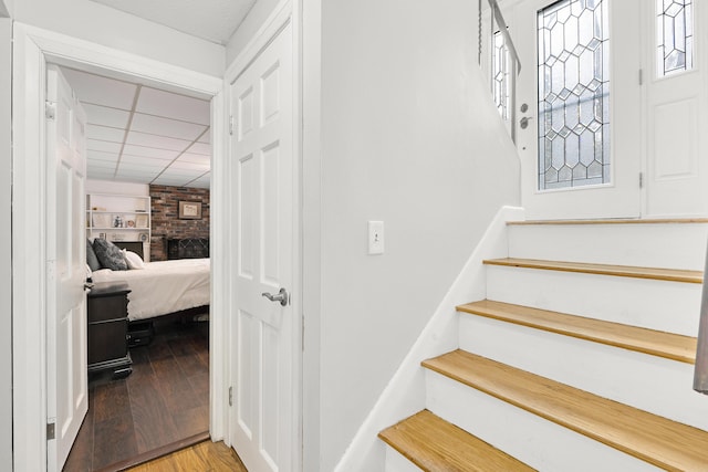 staircase featuring built in shelves, wood finished floors, and a paneled ceiling