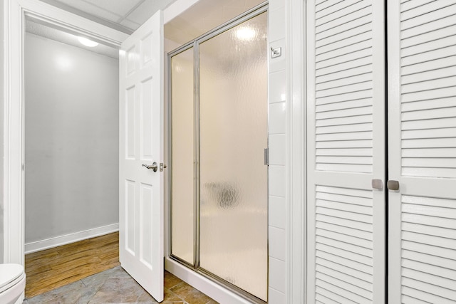 bathroom featuring a shower stall, toilet, and baseboards