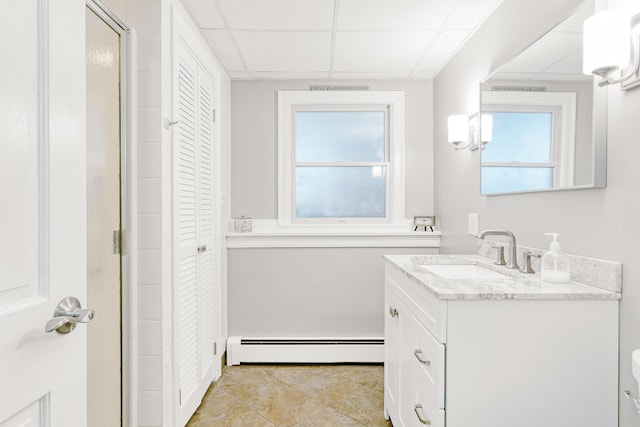 full bath featuring a baseboard heating unit, vanity, a closet, and a drop ceiling