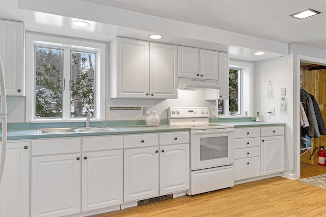 kitchen featuring light wood-type flooring, white range with electric cooktop, under cabinet range hood, a sink, and white cabinets