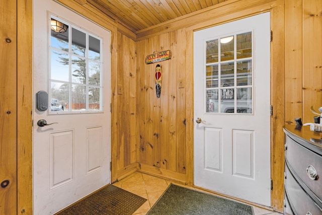 doorway to outside featuring light tile patterned floors, wooden walls, wooden ceiling, and crown molding