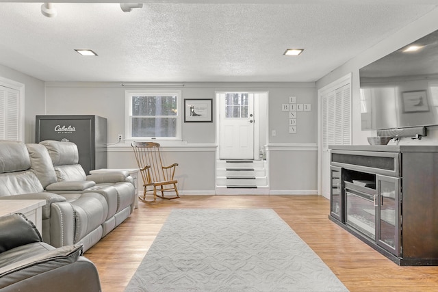 living area featuring light wood-style floors, baseboards, and a textured ceiling