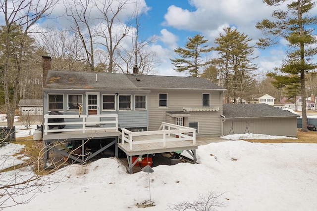 rear view of property with a deck, a shingled roof, and a chimney