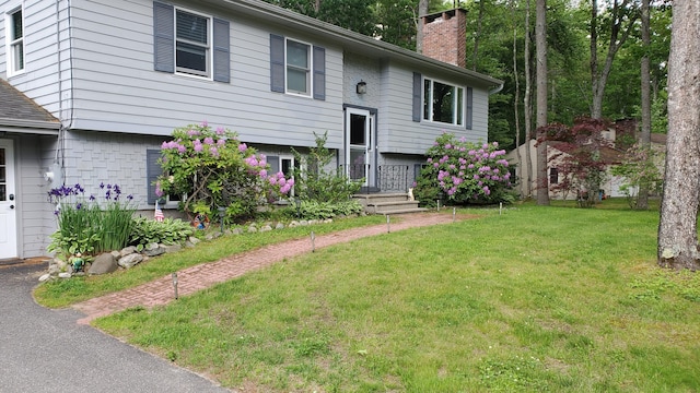 raised ranch with a front lawn and a chimney