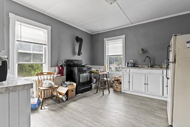 interior space featuring light wood-style flooring, gas stove, freestanding refrigerator, and a sink