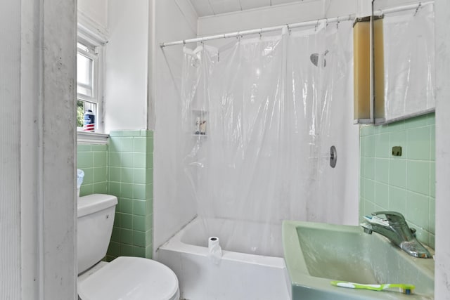 bathroom with a sink, toilet, tile walls, and shower / tub combo with curtain