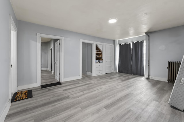 interior space featuring light wood-style flooring, radiator heating unit, and baseboards