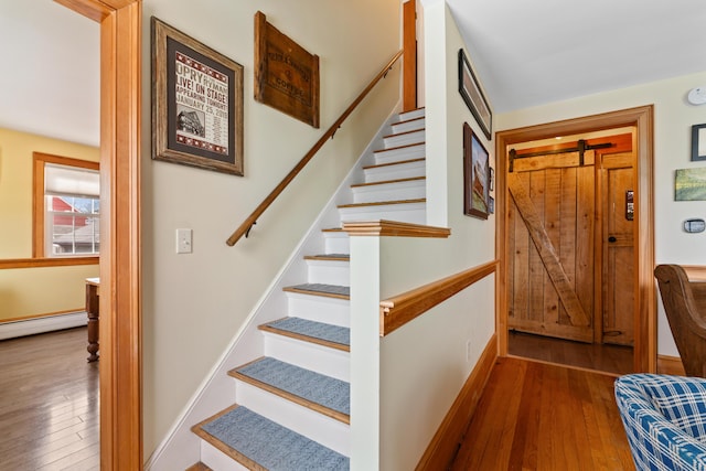 staircase with a baseboard heating unit, hardwood / wood-style flooring, and baseboards