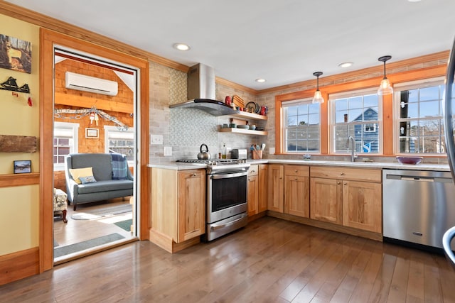 kitchen with a wall mounted AC, dark wood finished floors, a sink, appliances with stainless steel finishes, and wall chimney range hood