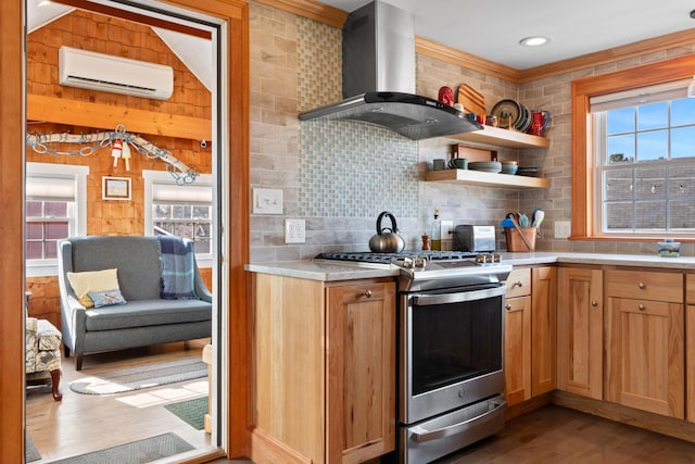 kitchen featuring a wall mounted AC, wall chimney range hood, light countertops, decorative backsplash, and gas range