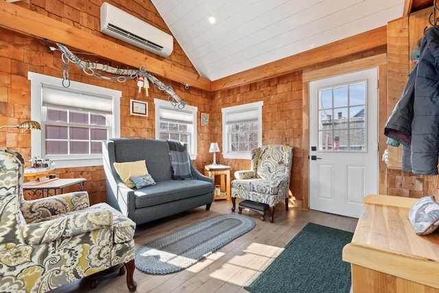 living room featuring vaulted ceiling, a healthy amount of sunlight, wood-type flooring, and a wall mounted AC