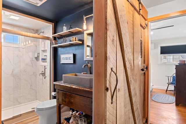 full bath featuring a marble finish shower, toilet, and wood finished floors